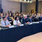 Homens e mulheres estão sentados em grande auditório