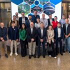 Homens e mulheres estão em pé lado a lado e olham para a câmera