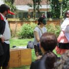 Pessoas com figurino estão em pé apresentado peça de teatro em área aberta