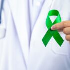Médico de jaleco segura laço verde símbolo do Abril Verde
