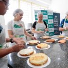 Mulheres com aventais e toucas preparam bolos em cozinha