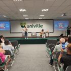 Pessoas se apresentam em palco durante evento e são observadas por plateia