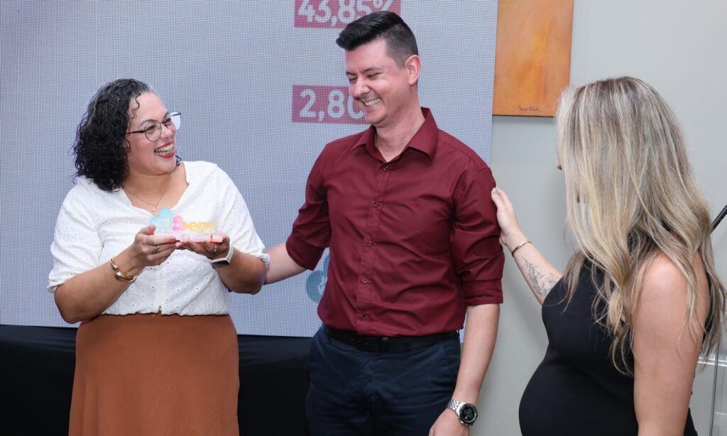 Homem e mulher sorriem enquanto seguram o troféu do Joinville Faz Bem