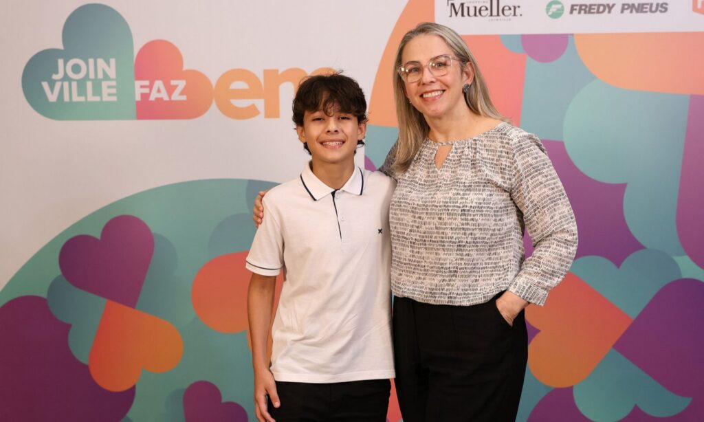 Uma mulher loira e um menino estão em pé e posam juntos para a foto