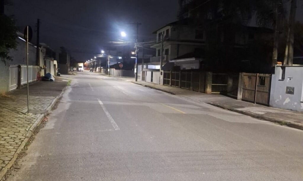 Rua pavimentada com iluminação noturna modernizada, mais clara