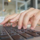 Imagem mostra duas mãos digitando em um teclado de notebook