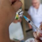 Mulher manipula frasco e seringa com vacina