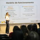 Palestrante no palco do evento, diante de uma tela