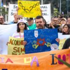 Diversas pessoas, entre homens e mulheres, seguram cartazes coloridos que falam sobre saúde mental enquanto caminham