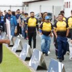 Homens de várias idades usam uniforme amarelo e preto e desfilam em frente a outros já posicionados em fila