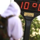Termômetro instalado em rua mostra temperatura de 10 graus. Próximo a ele, há uma pessoa de costas, usando moletom com capuz