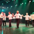Mulheres da terceira idade apresentam coreografia de dança em palco