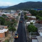 Imagem aérea mostra máquinas trabalhando na pavimentação de uma rua residencial