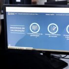 Imagem mostra pessoa, parcialmente aparente, acessando o site da Prefeitura em tela sobre o Programa de Valorização