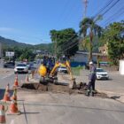 Imagem mostra trabalhador e máquina próximos a uma grande vala em uma rua pavimentada de Joinville