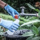Pessoa abrindo uma torneira com verde de fundo, colocando água em uma garrafa