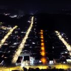 Imagem área mostra três ruas com iluminação mais clara, enquanto uma rua entre elas está com iluminação amarelada