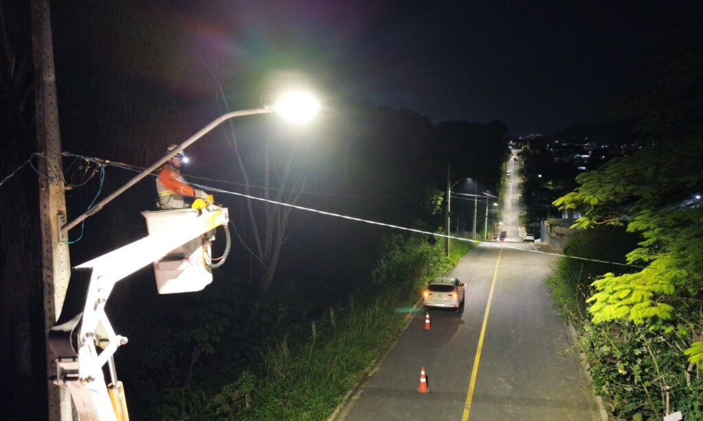 Homem está em pé em um cesto elevado perto de um poste aceso.