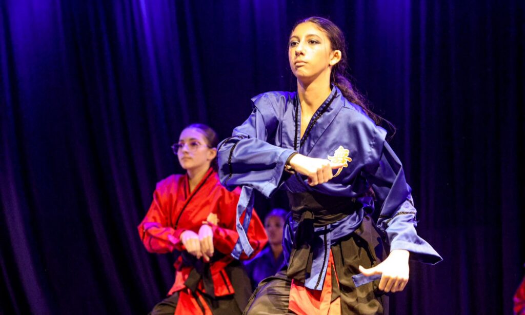 Duas adolescentes com figurino que remete à cultura japonesa dançam em um palco