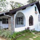 Casa branca, com janelas arredondas, canteiro de plantas e gramado na frente, onde fica o Museu Casa Fritz Alt