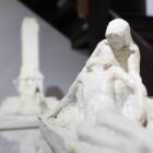 Imagem mostra escultura branca que remete a um homem deitado sobre o colo de uma mulher