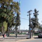 Imagem mostra praça com árvores e pessoas caminhando. Ao fundo, está o imóvel do terminal central de transporte coletivo