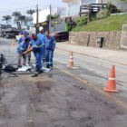 Imagem mostra homens uniformizados trabalhando em obra de asfalto em rua pavimentada