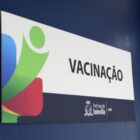 Imagem mostra uma placa escrito Vacinação em uma porta azul