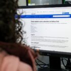 Imagem mostra mulher com cachos de costas, observando a tela de um computador em uma página no site da Prefeitura de Joinville sobre cadastro de voluntários para a Defesa Civil