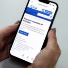 Mulher segura celular e na tela está no site da Prefeitura de Joinville