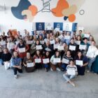 Dezenas de pessoas, entre homens e mulheres, seguram certificados e sorriem para a foto