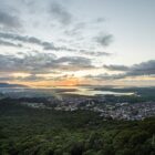 Imagem aérea de Joinville mostra área de vegetação, a Baía Babitonga e área urbana, com prédios e outras construções