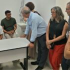 Imagem mostra sete pessoas, entre homens e mulheres, em um consultório médico. Eles conversam entre si