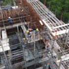 Imagem aérea das obras da Ponte Joinville mostram trabalhadores uniformizados e de capacete trabalhando em uma estrutura repleta de ferros