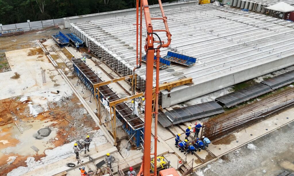 Imagem aérea mostra grande terreno dezenas de vigas de concreto que serão usadas na Ponte Joinville
