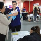 Duas mulheres seguem um cachorro branco de pequeno porte no colo