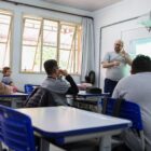 Professor, em sala de aula, se comunicando por meio da linguagem de libras com alunos
