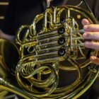 Mão masculina segura instrumento de sopro dourado