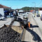 Imagem mostra uma máquina de fresagem jogando o asfalto removido da pista na caçamba de um caminhão