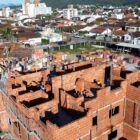 Imagem mostra obras do Residencial Areia Branca, com três andares em construção, tijolos à vista e trabalhadores na obra