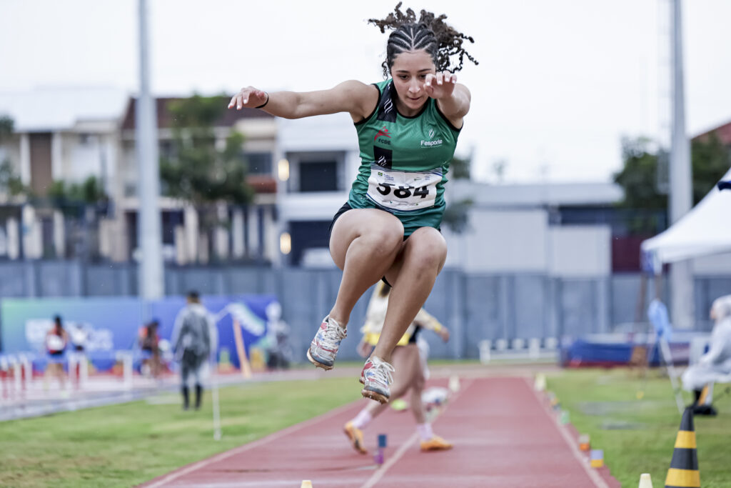 Foto mostra jovem pulando em pista de atletismo