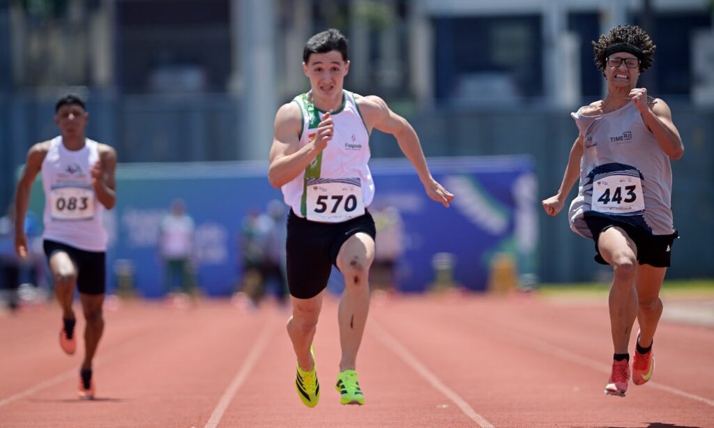 Três jovens correm rapidamente em uma pista de atletismo
