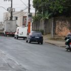 Foto mostra carros, moto e caminhões passando por rua com asfalto novo