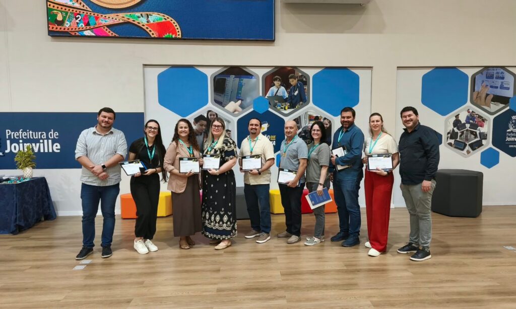 Foto mostra dez pessoas, entre homens e mulheres, em pé, com medalhas no pescoço, posando para a foto.